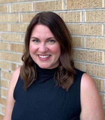 Woman in blue shirt standing against a brick wall