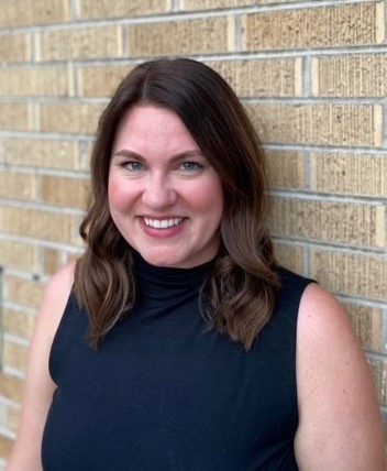 Woman in blue shirt standing against a brick wall