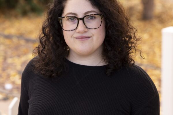 Woman with brown, curly hair poses in a Fall scene